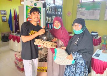 Kepala Sekolah SDIT Mutiara Yasmainisyar menyerahkan bantuam kepada masyarkat.