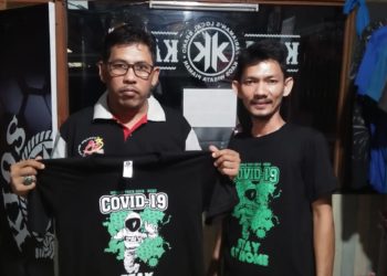 Dewe (kanan) bersama salah satu pelanggan memperagakan kaos "stay at home".