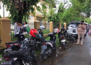 Relawan Mahyeldi Audy membuka APK yang terpasang di pagar salah satu kantor pemerintah.